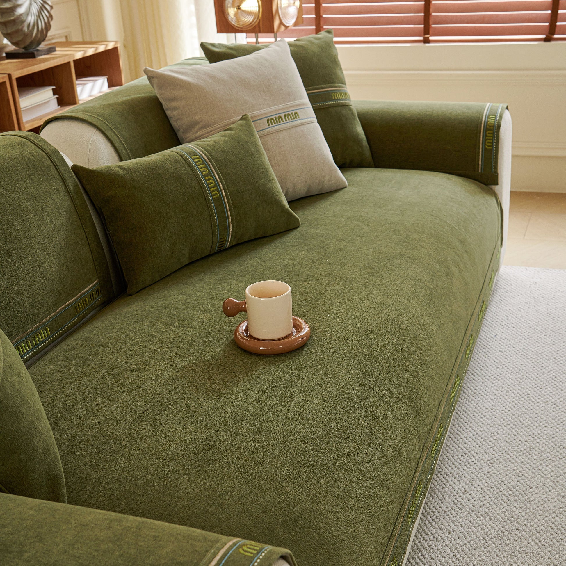 Chenille Sofa Cover Pet Mat, Non-Slip Couch Protector for Sectional & L-Shaped Sofas in green with cushions and a cup.