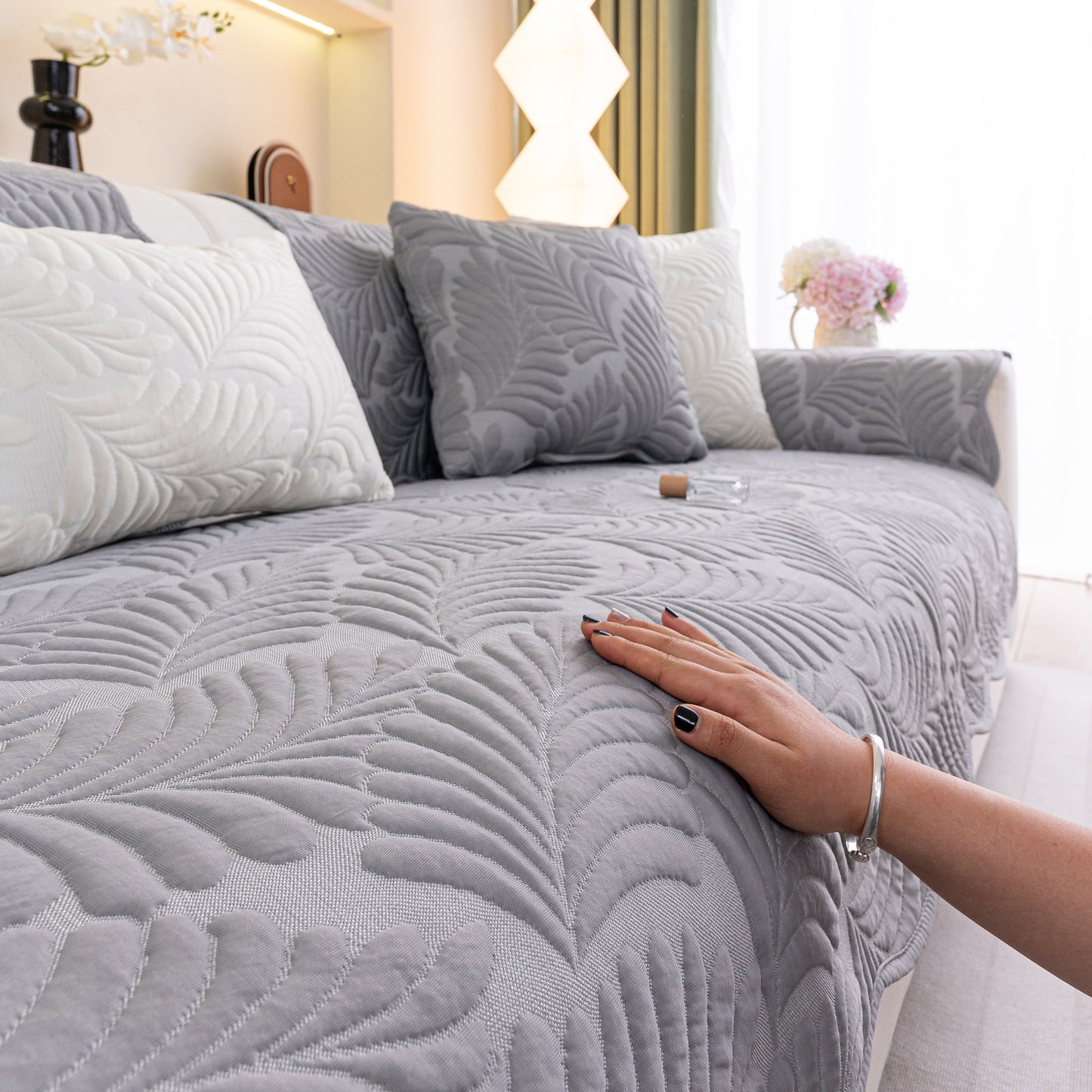 Sofa Cover for Leather & Fabric Couches, 3D Leaf Embossed Quilted Furniture Covers in gray, close-up view with hand touching the fabric