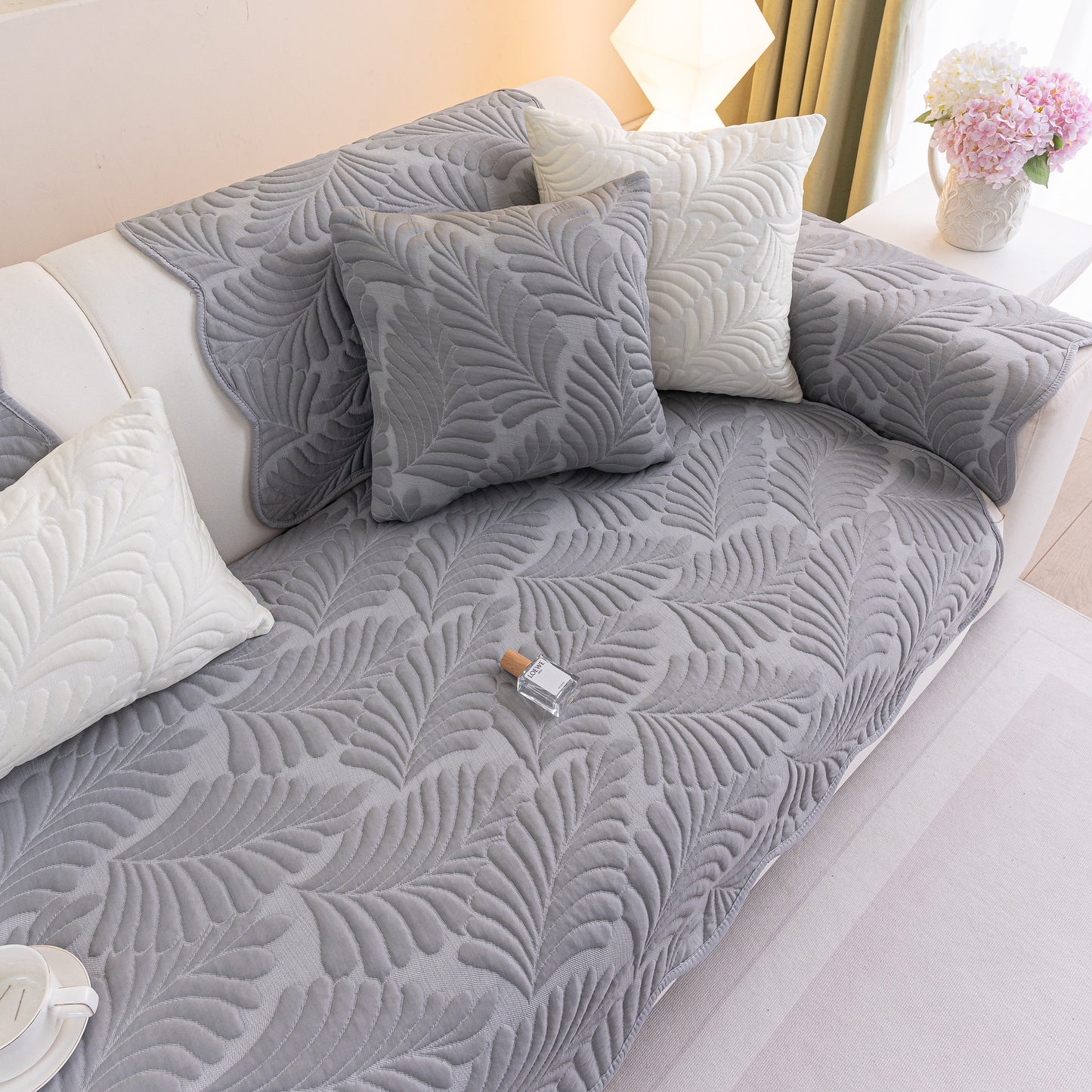 Sofa Cover for Leather & Fabric Couches, 3D Leaf Embossed Quilted Furniture Covers in gray with decorative pillows on a sofa.