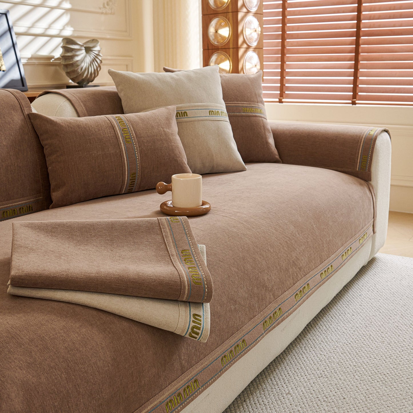 Chenille Sofa Cover Pet Mat, Non-Slip Couch Protector for Sectional & L-Shaped Sofas in a living room setting with pillows and a mug.
