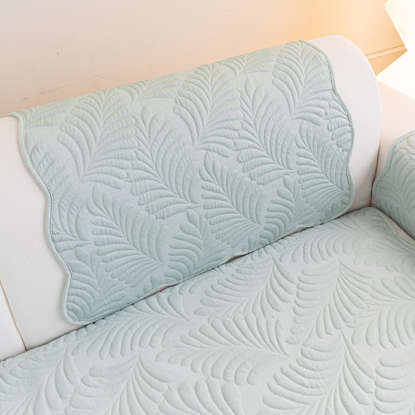 Sofa Cover for Leather & Fabric Couches, 3D Leaf Embossed Quilted Furniture Covers with silicone anti-slip backing on a white sofa.