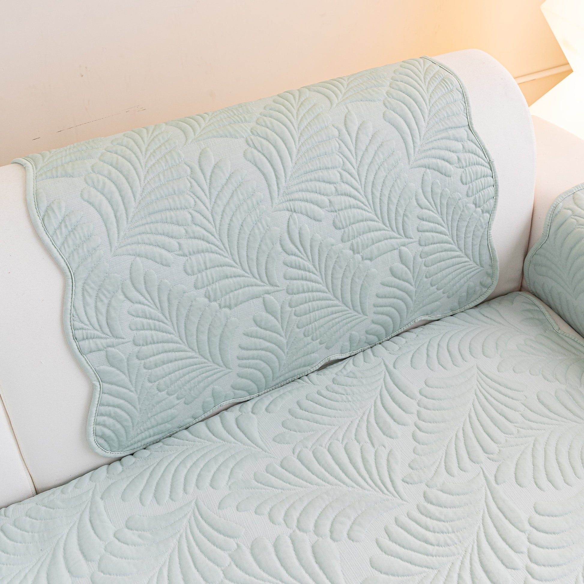 Sofa Cover for Leather & Fabric Couches, 3D Leaf Embossed Quilted Furniture Covers with silicone anti-slip backing on a white sofa.