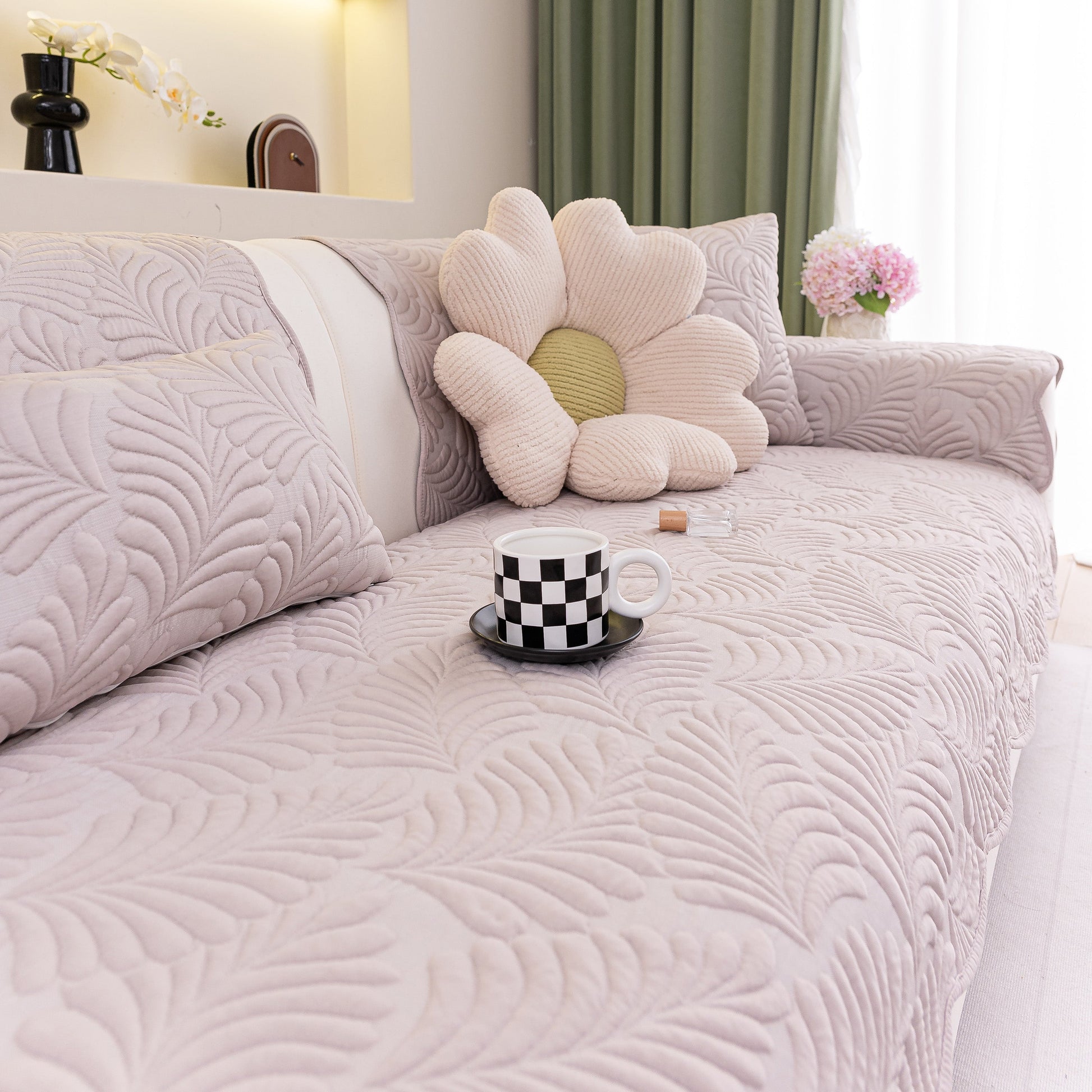 Sofa Cover for Leather & Fabric Couches, 3D Leaf Embossed Quilted Furniture Covers on a stylish beige couch with cushion and mug.