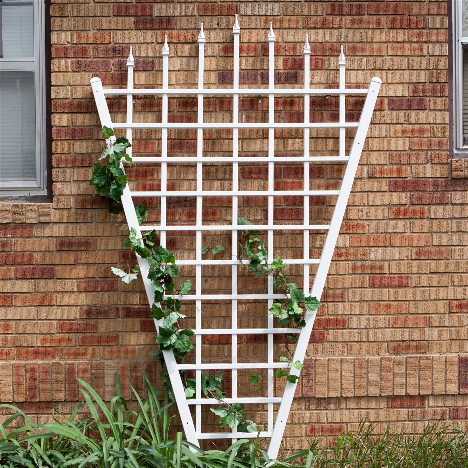 7.75 Ft Fan Shaped Garden Trellis with Pointed Finals in White Vinyl against a brick wall