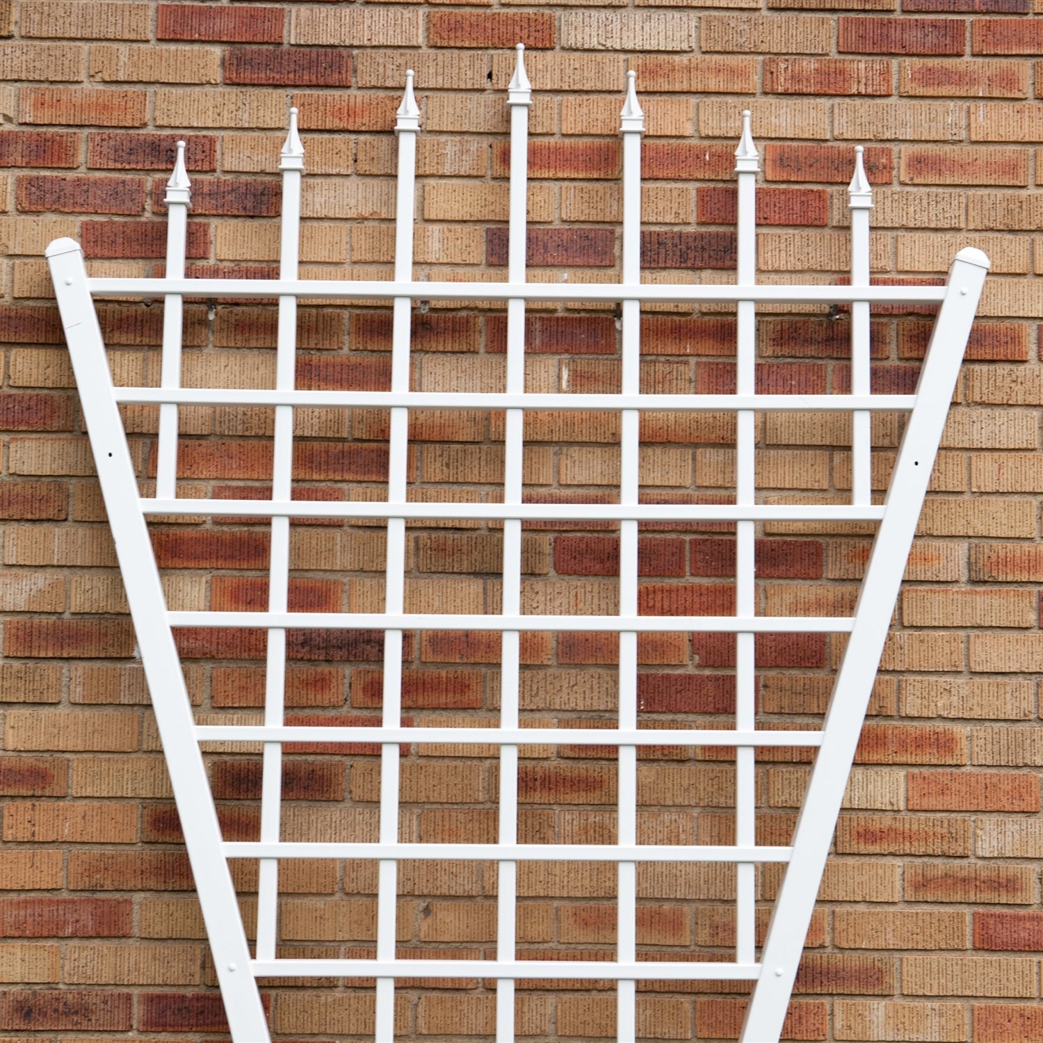 7.75 Ft Fan Shaped Garden Trellis with Pointed Finals in White Vinyl against brick wall