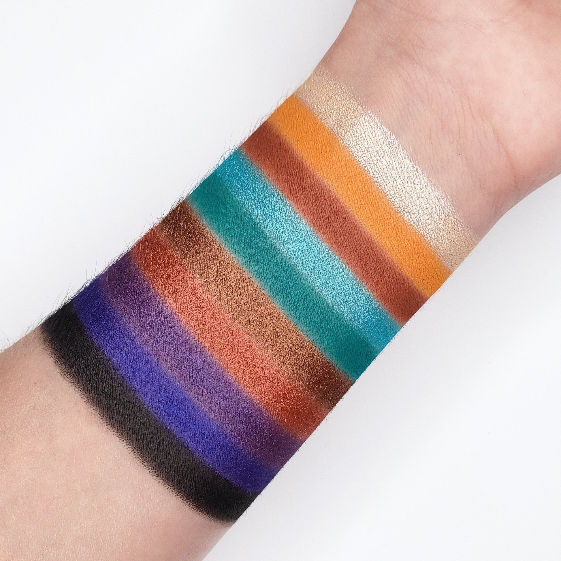 Swatches of the 10 Color OMG Eyeshadow Collection OMG10 showcasing vibrant, multi-dimensional shades on a forearm.