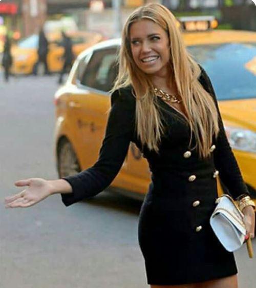 Woman in Sophisticated Black Gold Button Dress standing in front of yellow taxi on city street, showcasing elegant style.