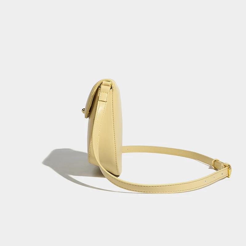 Side view of a yellow handbag with a sleek strap design on a white background.