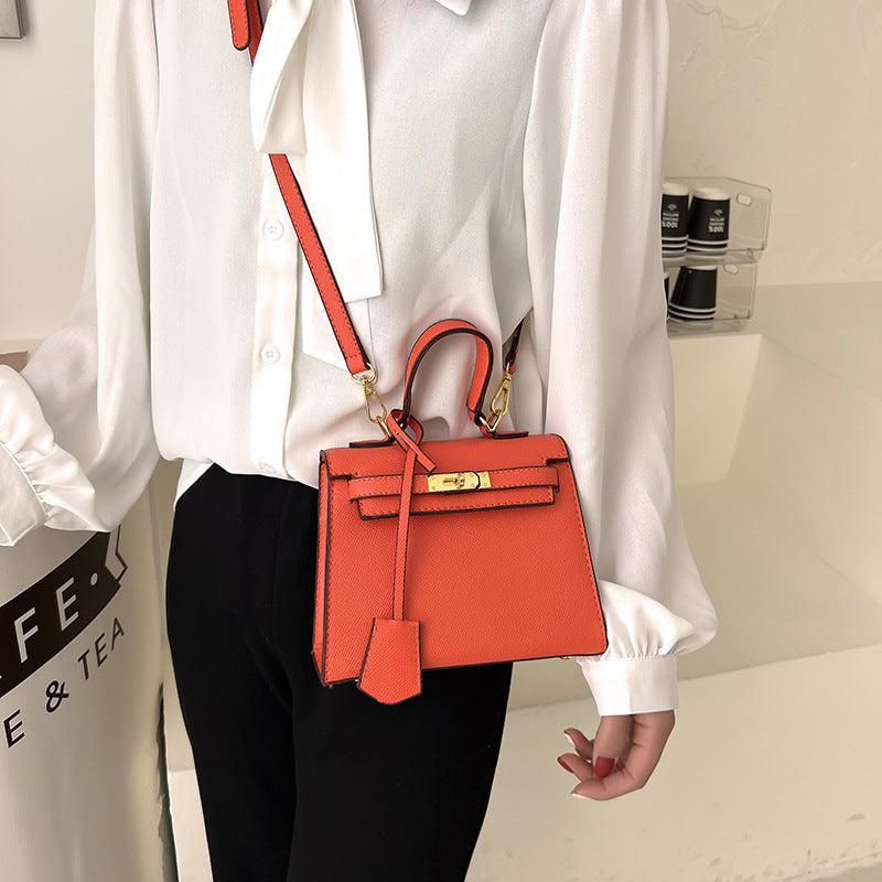 Luxury Cowgirl Kelly Purse – Trendy, High-Fashion Leather Handbag with Adjustable Strap in orange, worn crossbody by a woman in a white blouse.