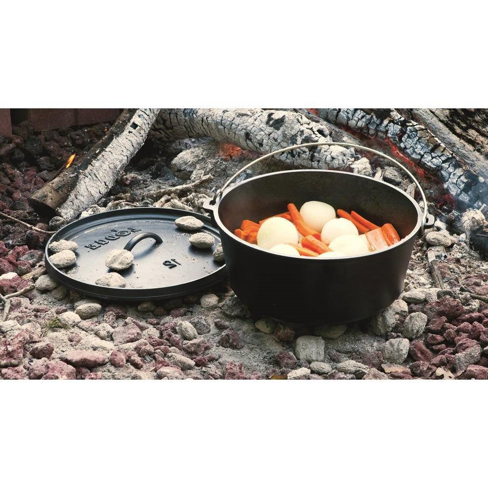 8-Quart Deep Seasoned Cast Iron Dutch Oven with Lid and Metal Handle used outdoors with vegetables inside.