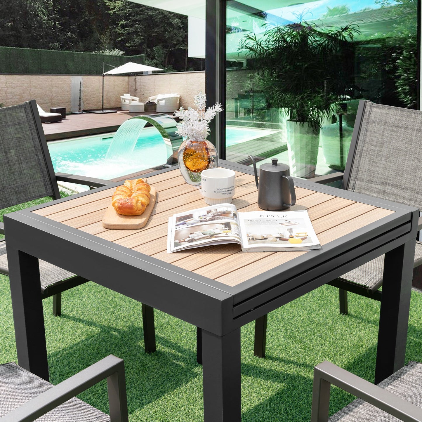 31.5-63 Inches Extendable Patio Table for 4-6 People-Natural in a garden setting with chairs and decorative items on top.