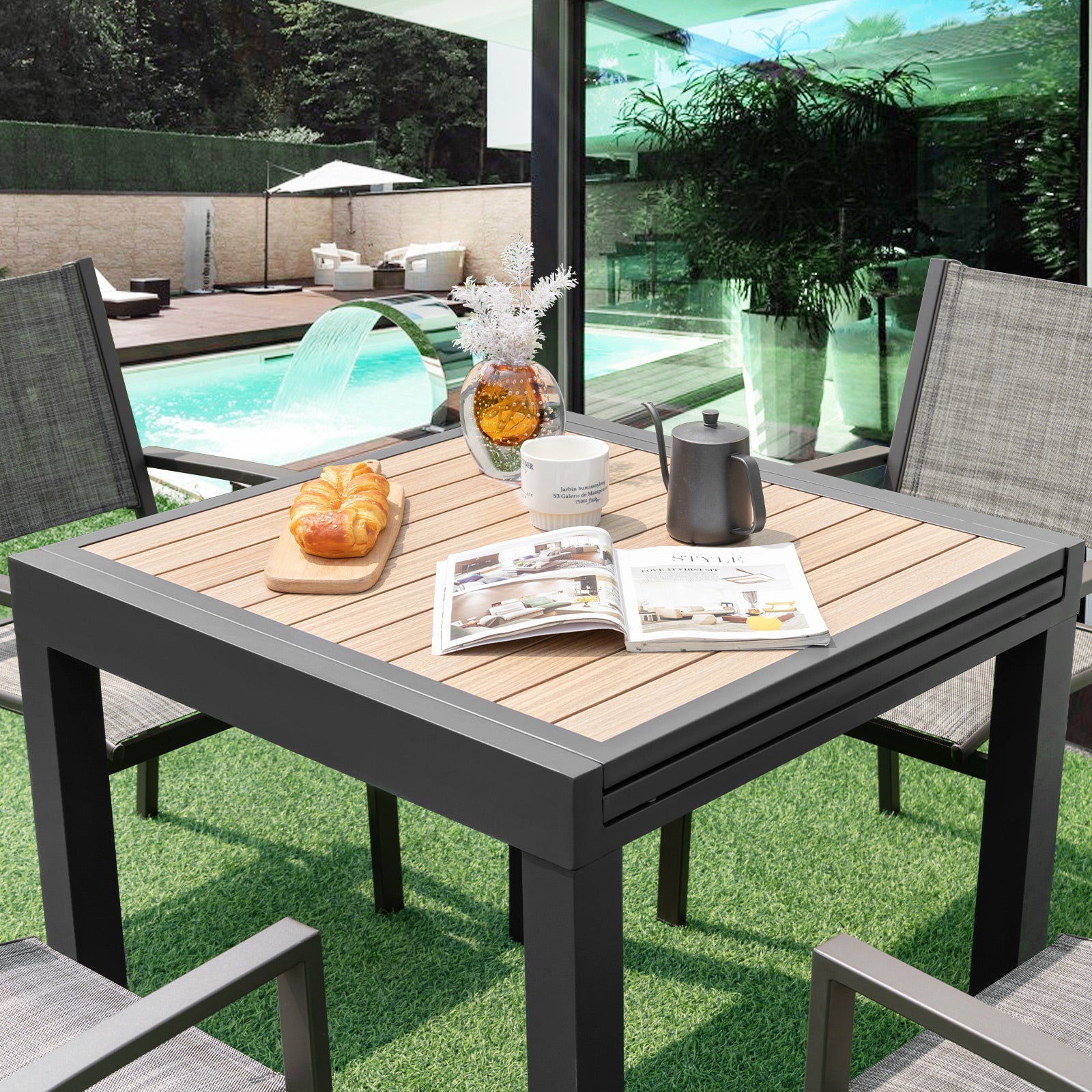 31.5-63 Inches Extendable Patio Table for 4-6 People-Natural in a garden setting with chairs and decorative items on top.