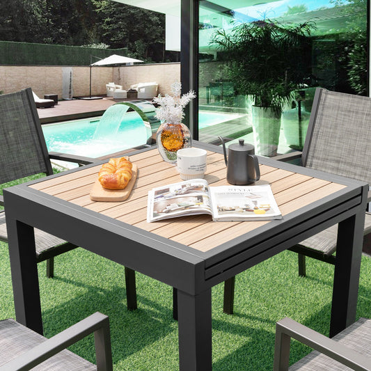 31.5-63 Inches Extendable Patio Table for 4-6 People-Natural in a garden setting with chairs and decorative items on top.