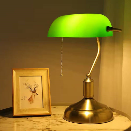 Antique Brass Bankers Lamp Desk Light Table Lamp with Green Glass Shade on marble table next to framed deer artwork.