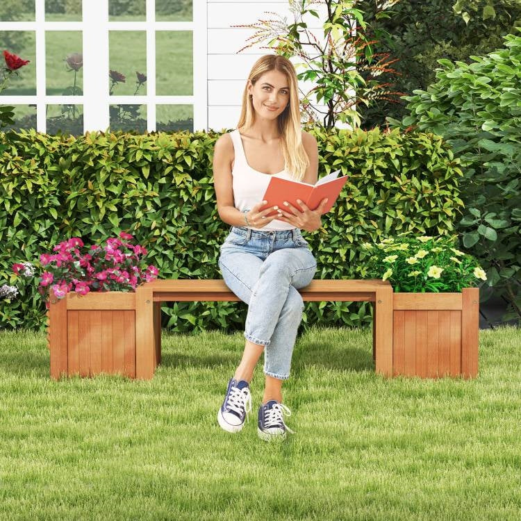 Woman reading on a Farmhouse Durable Outdoor Wooden Planter Box with Garden Bench, surrounded by lush green garden and vibrant flowers.