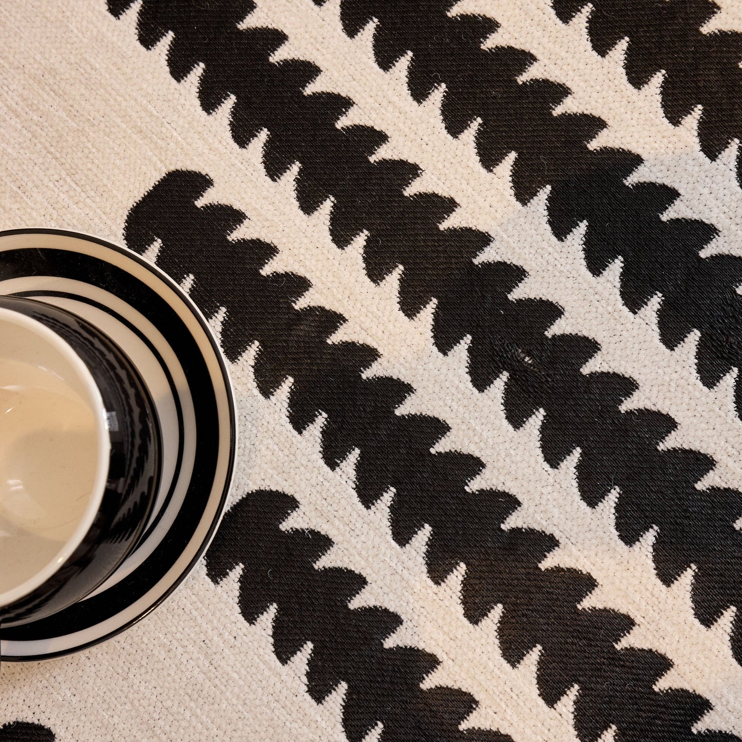 Black and white geometric pattern on fabric with a striped coffee mug