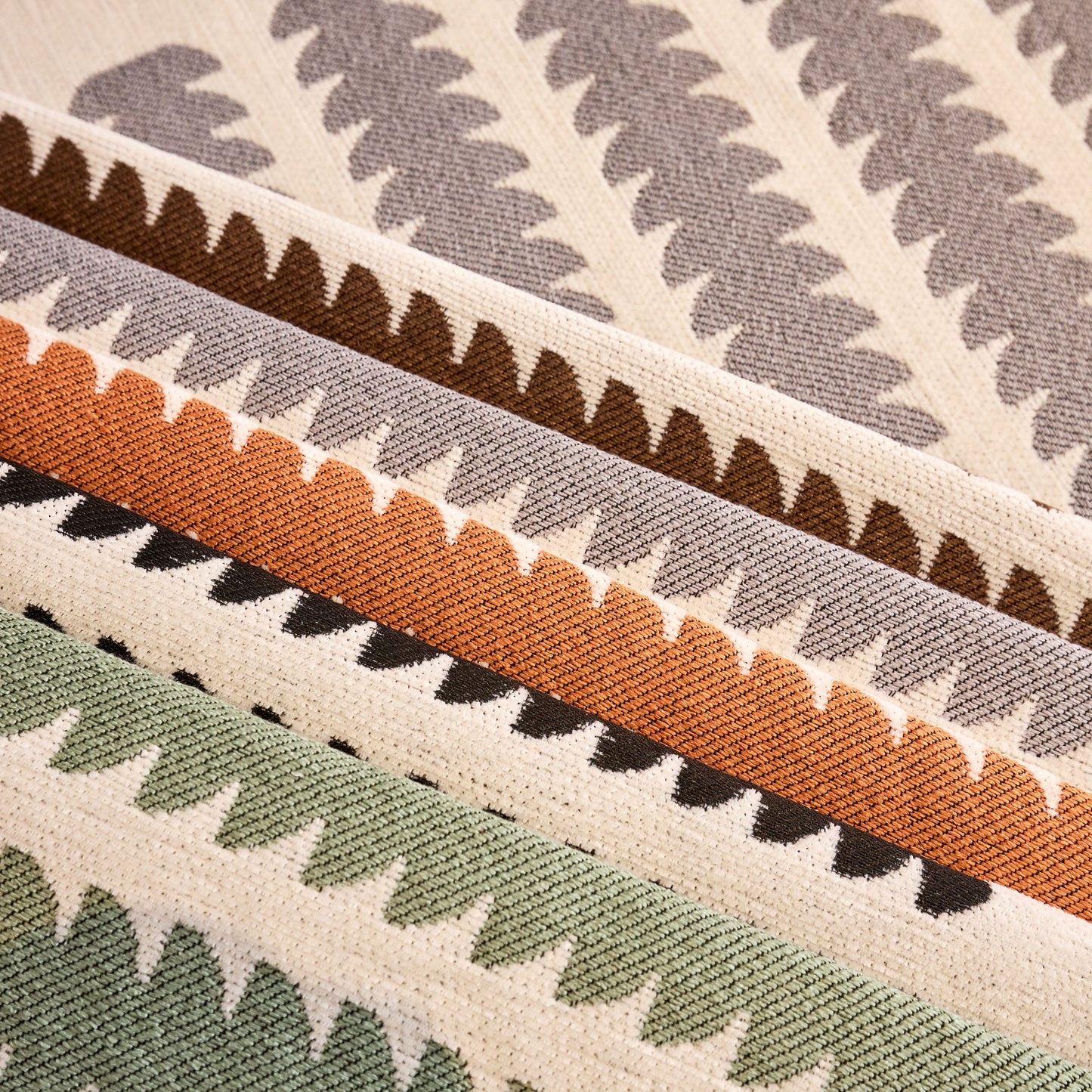 Close-up of textured fabric with abstract zigzag geometric pattern in beige, brown, orange, and green color stripes.