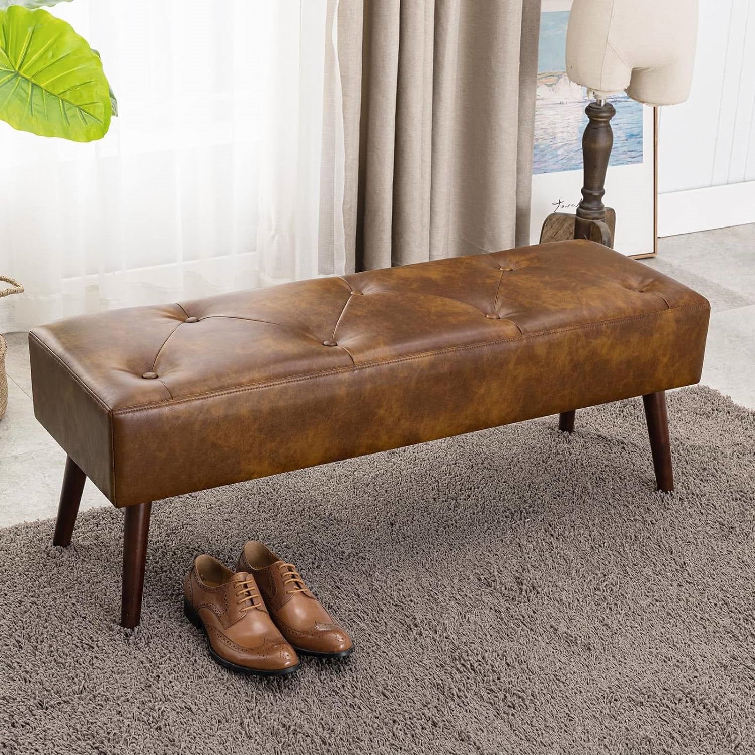 Mid-Century End of Bed Bench with Brown Leather Upholstered Seat Solid Wood Legs in bedroom setting with shoes on rug