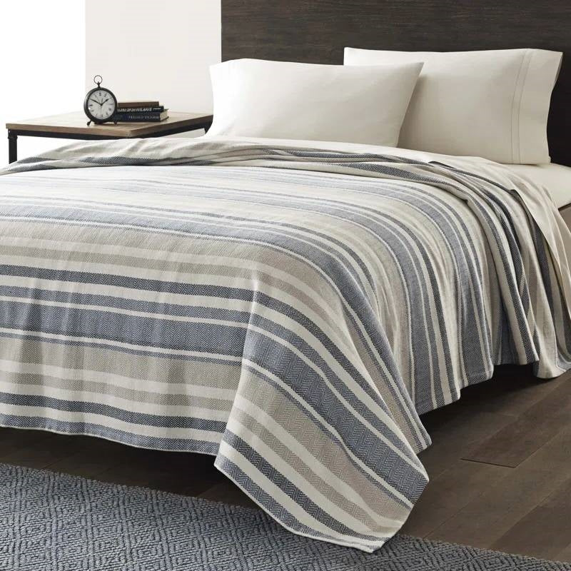 Full/Queen size Navy Blue Tan Cream Chevron Stripe Lightweight Cotton Blanket on bed with pillows.