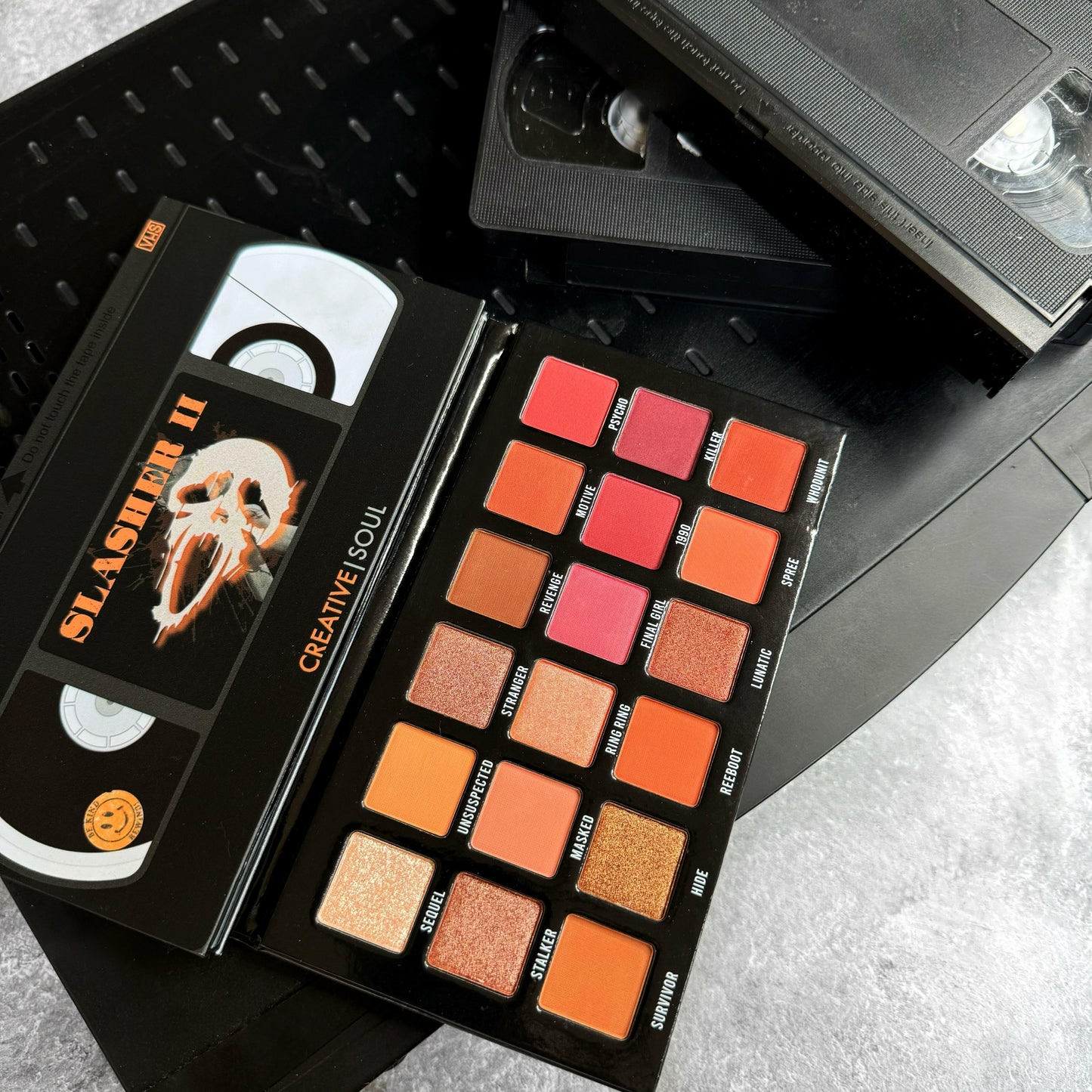Slasher II Eyeshadow Palette with horror-inspired neutral shades and VHS tape design, perfect for 90's themed makeup.