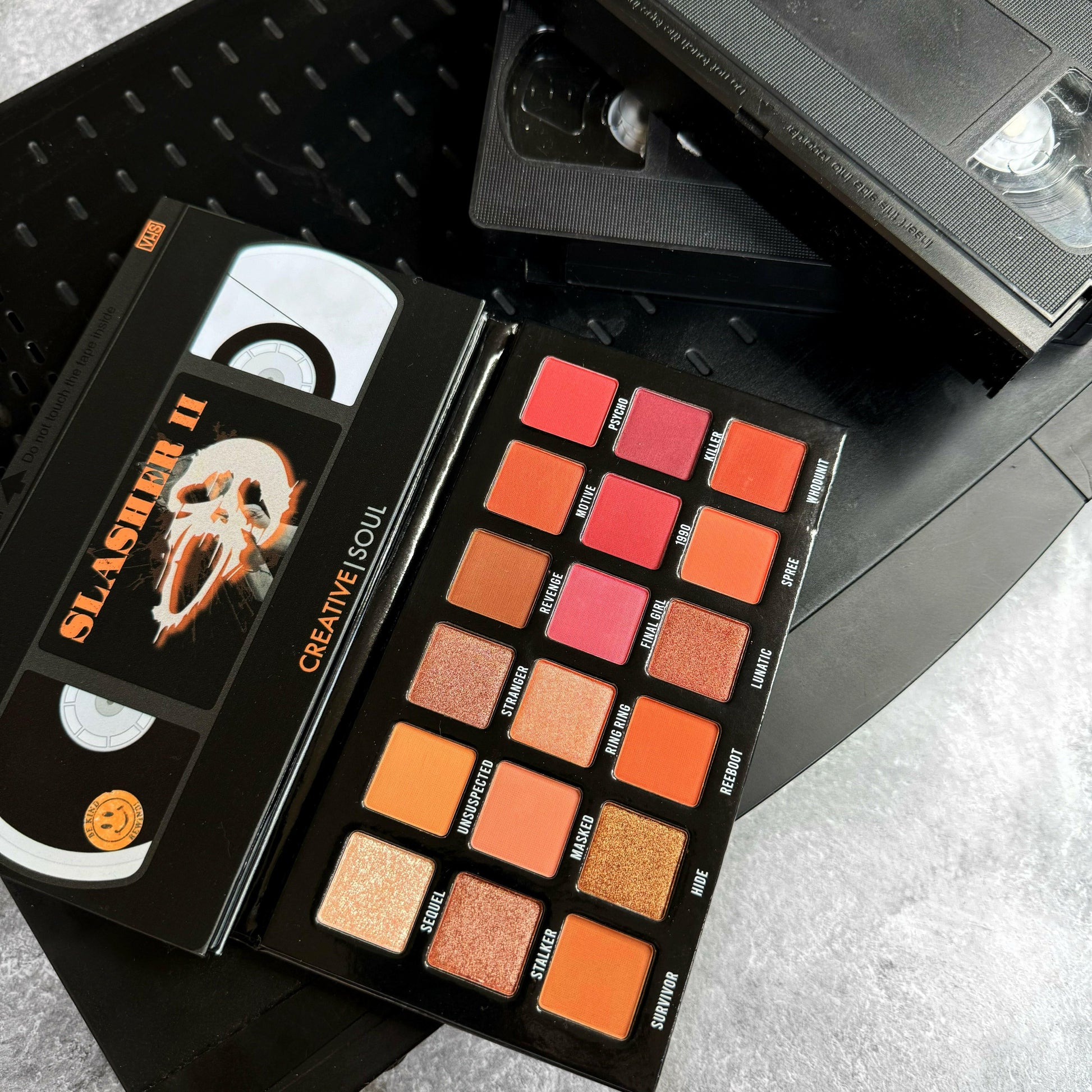 Slasher II Eyeshadow Palette with horror-inspired neutral shades and VHS tape design, perfect for 90's themed makeup.