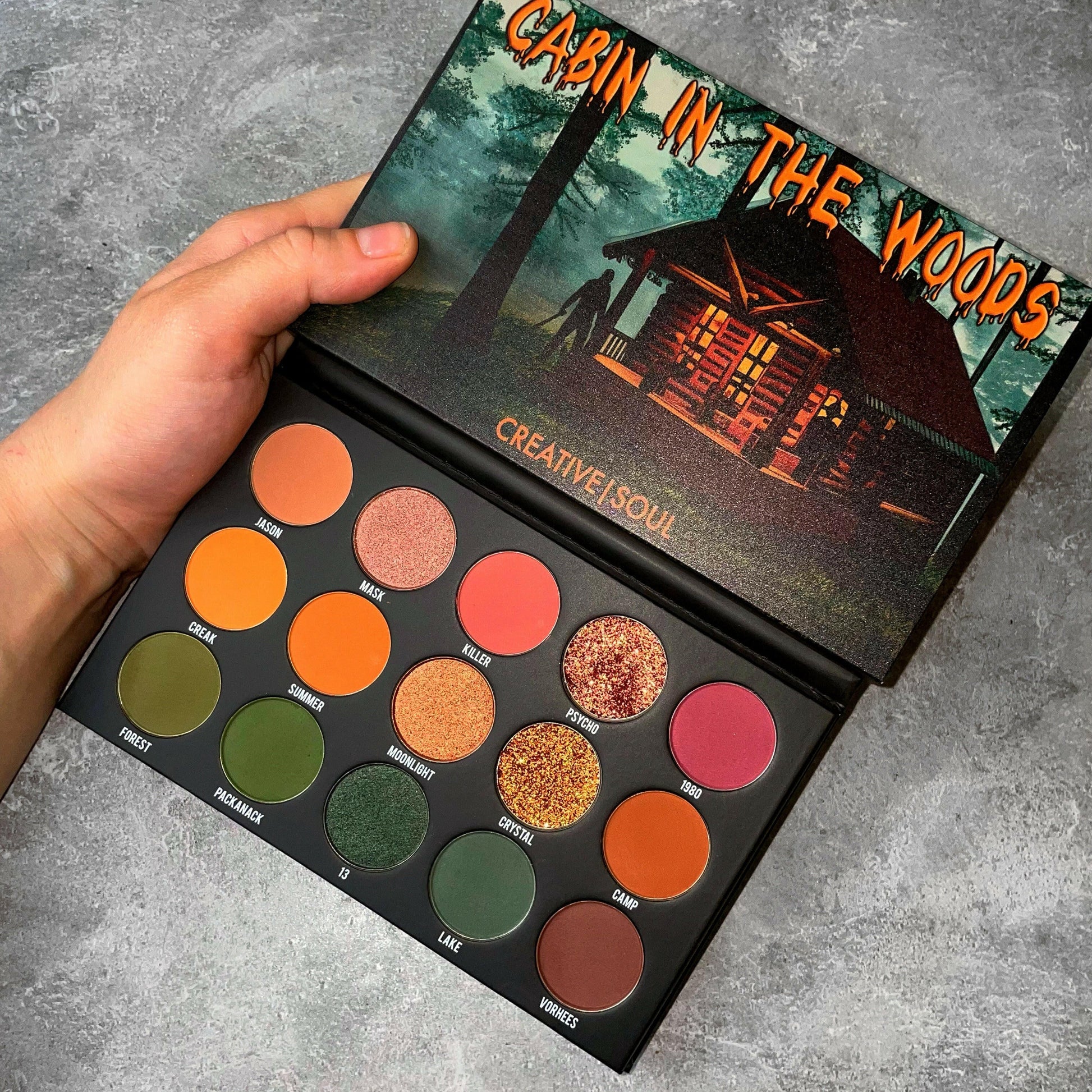 Cabin In The Woods Eyeshadow Palette with 80’s slasher film-inspired colors in mauves, pinks, oranges, and greens.