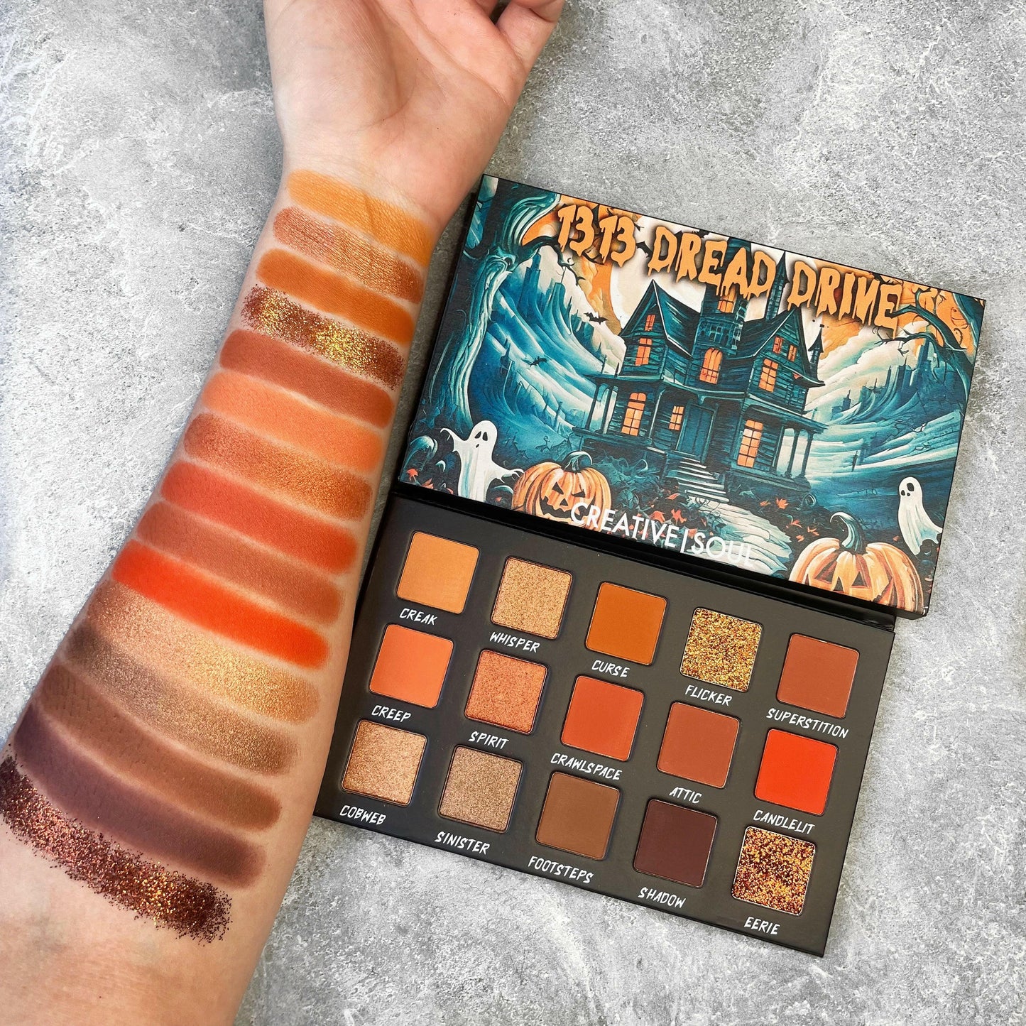 1313 Dread Drive Eyeshadow Palette with swatches on arm, showcasing Halloween-inspired neutral shades.