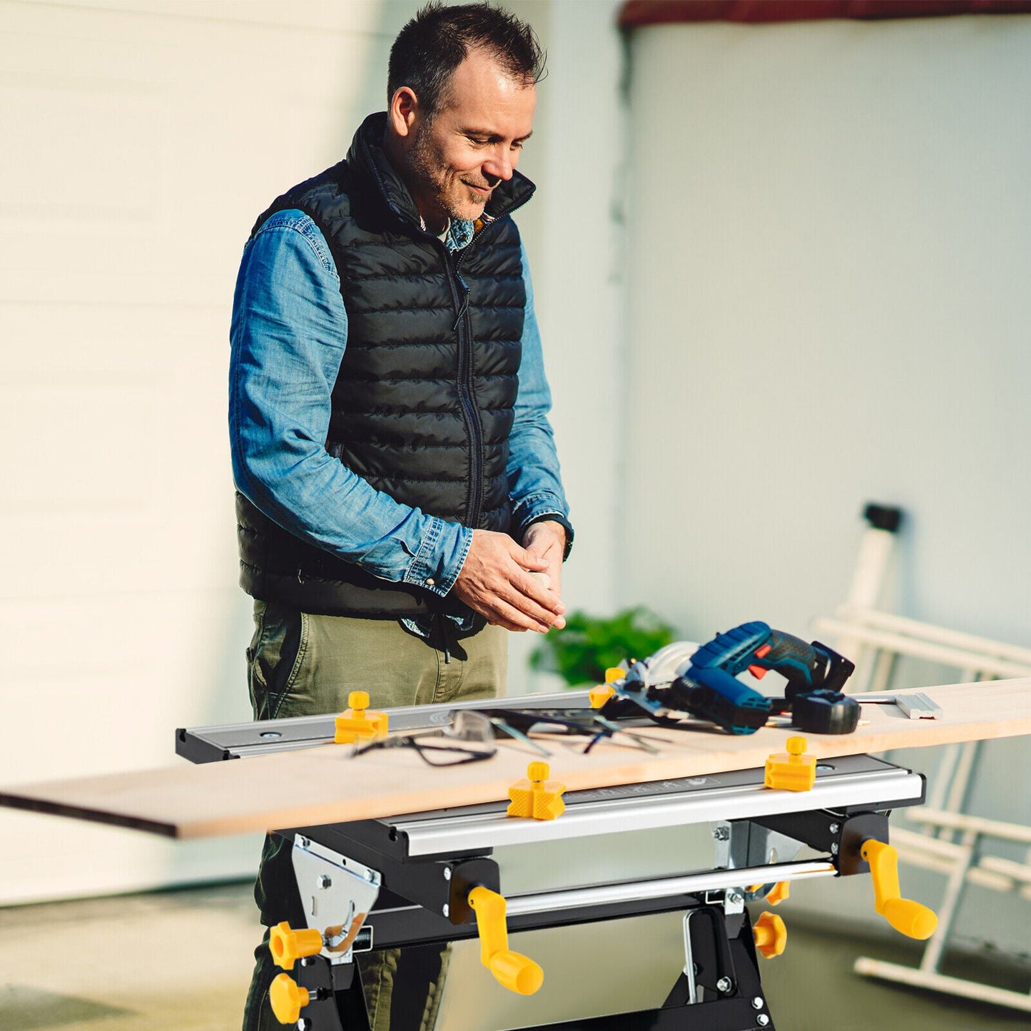 Man using Folding Work Table with Tiltable Platform and 7-level Adjustable Height-Black in a workshop setting