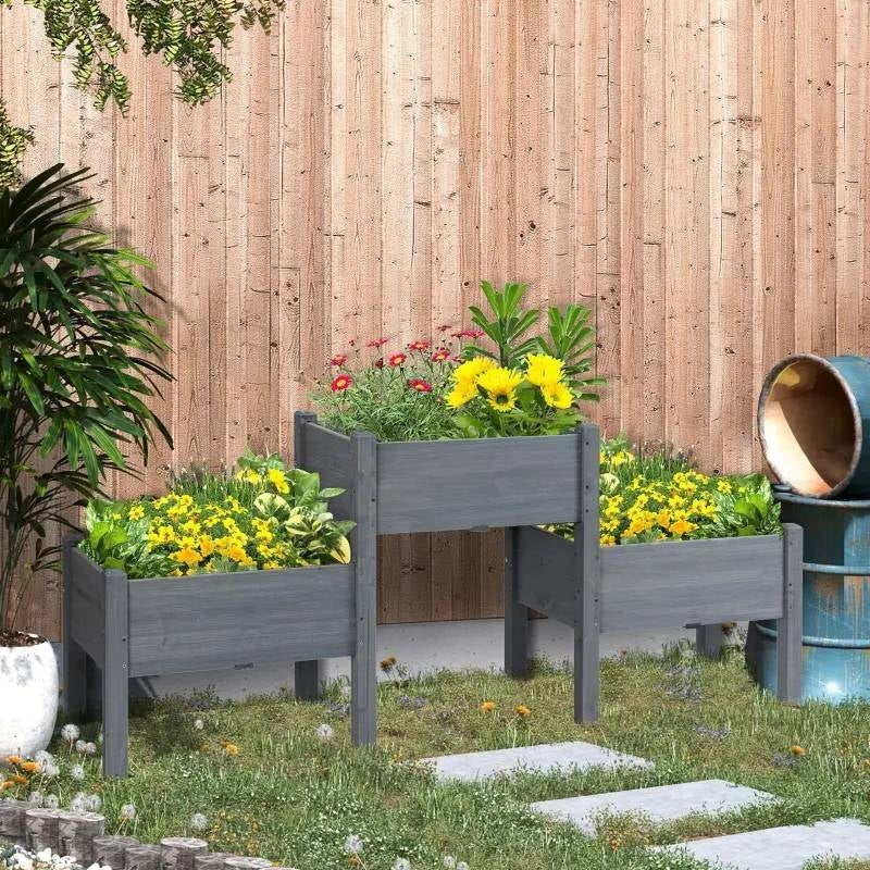 3 Grey Wood Elevated Planter Set Vegetable Herb Flowers Raised Garden Beds with vibrant yellow and red flowers in backyard.