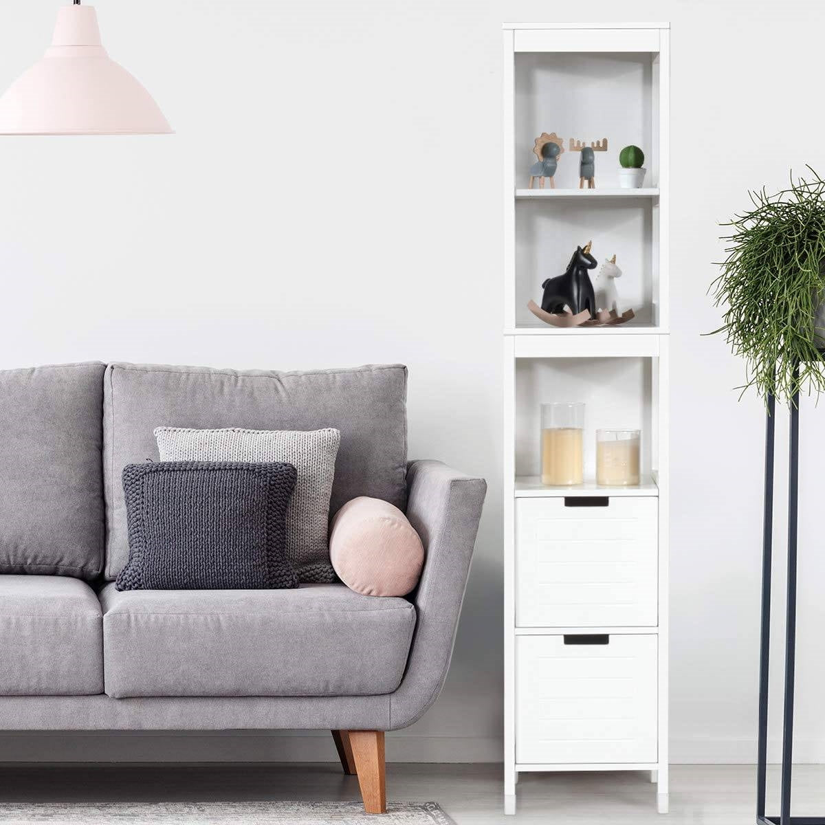 Bathroom Cabinet Tower with 2 Storage Drawers and 3 Shelves in White Wood Finish beside a grey sofa in a modern living room.
