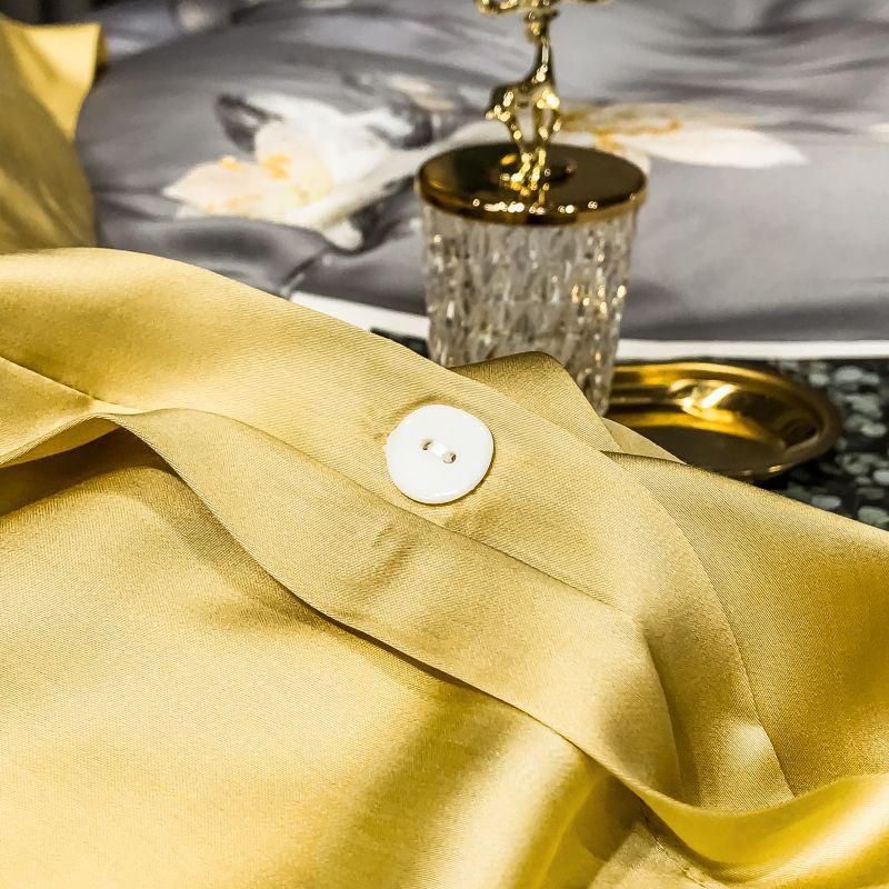 Detail of the luxurious Orquidea Clara Duvet Cover Set (Eucalyptus Lyocell) in silk blend fabric showcasing button and gilt decor.