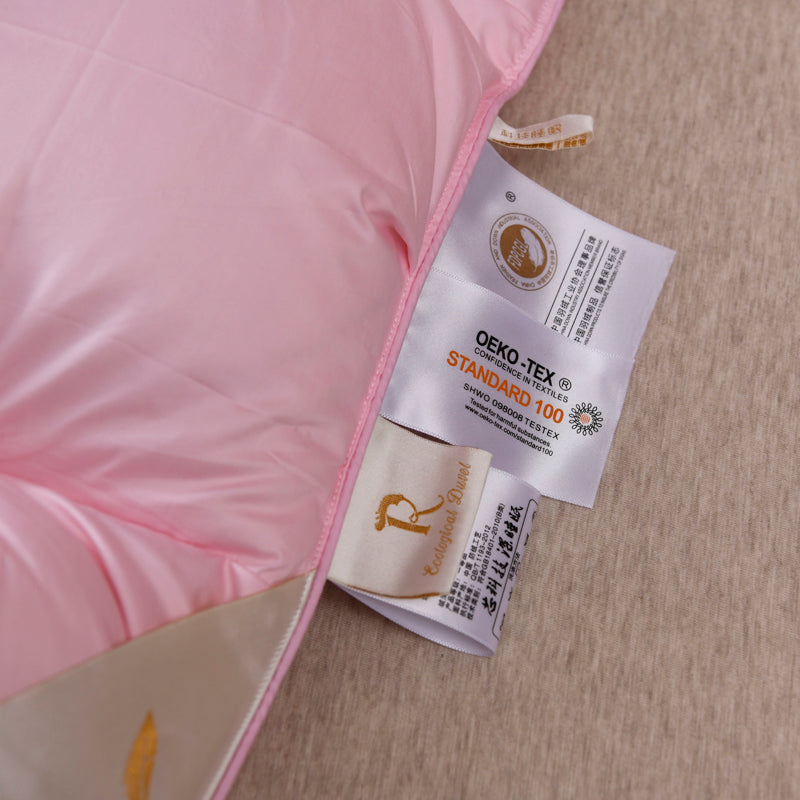 Close-up of Giuseppina 1000 Thread Count Goose Down Comforter Duvet showcasing quality labels and pink cotton fabric.