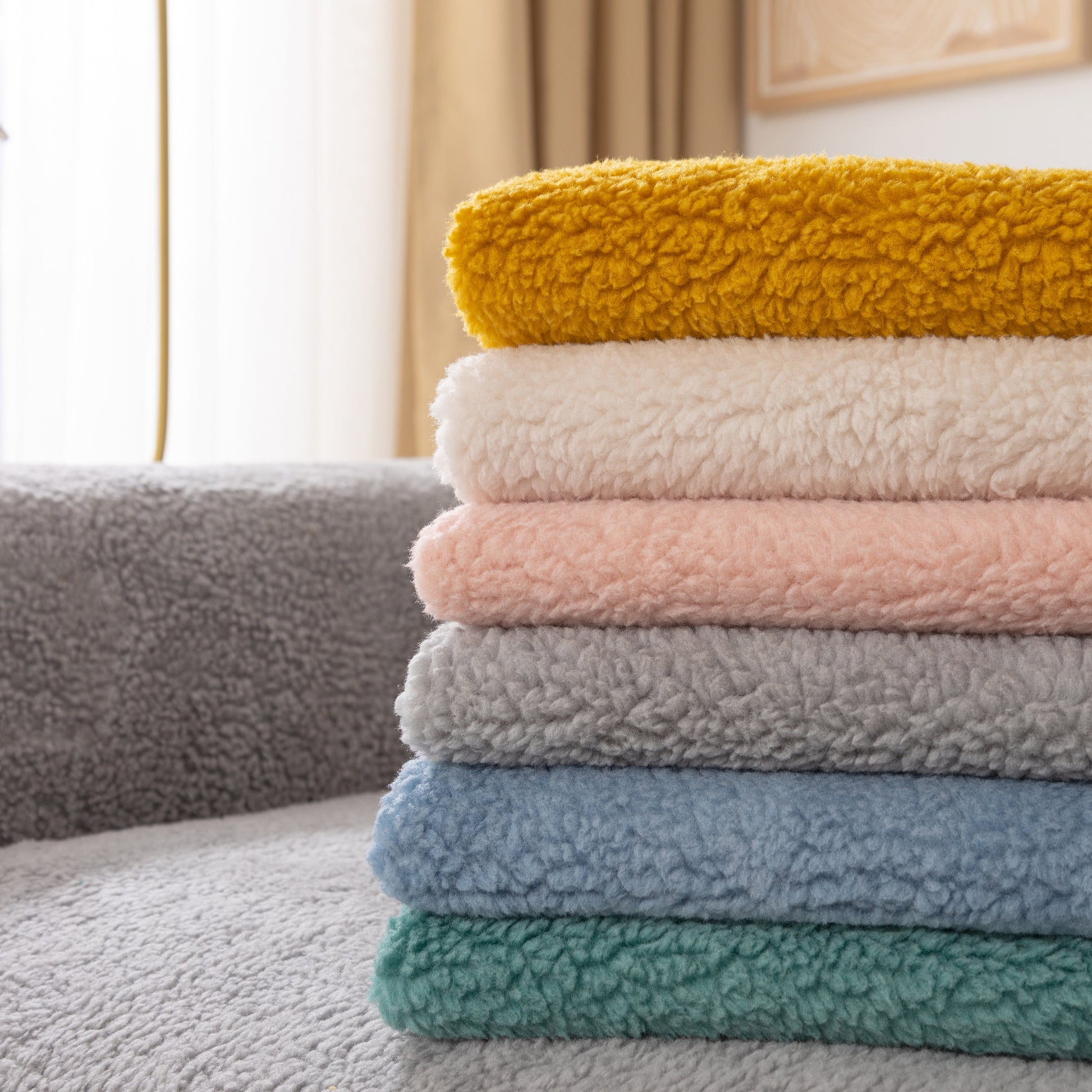 Stack of colorful Luxury Sherpa Fleece Solid Sofa Towels Thickened Plush Non Slip Sofa Cushion Covers on grey sofa.