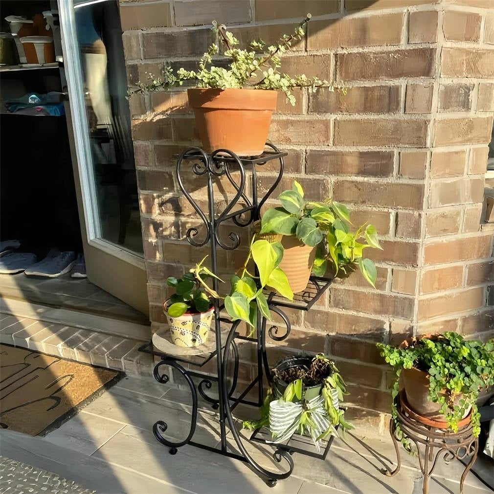 Elegant Black Metal 4-Shelf Plant Stand displaying plants against a brick wall, showcasing its iron art design and durability.
