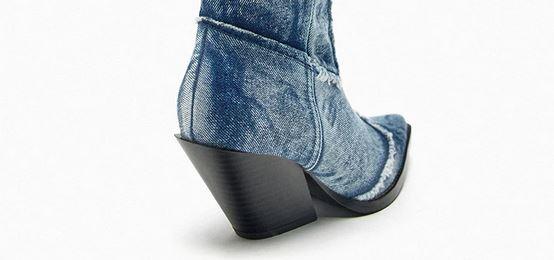 Close-up of the heel on Handcrafted Distressed Denim Knee-High Boots showcasing distressed denim and thick high heel.