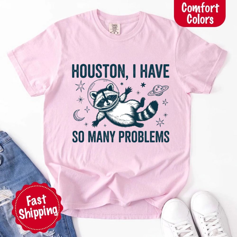 Houston I Have So Many Problems Raccoon Comfort Colors T-Shirts featuring raccoon in space on pink background with fast shipping.