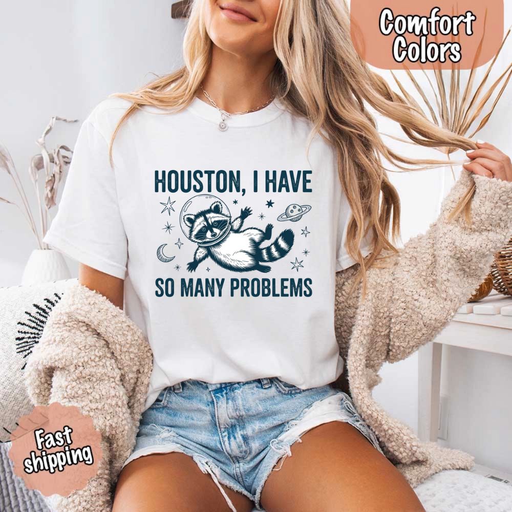 Houston I Have So Many Problems Raccoon Comfort Colors T-Shirts featuring a raccoon in space with humorous text on white cotton tee.