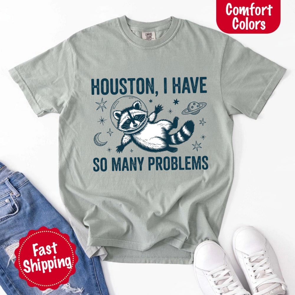 Houston I Have So Many Problems Raccoon Comfort Colors T-Shirts with a space-themed raccoon design on display.