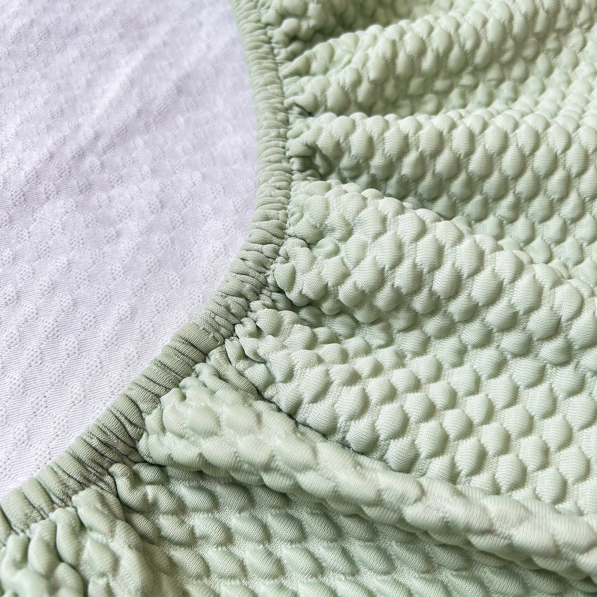 Close-up of textured Cooling Stretch Sofa Seat Cushion Covers, Slip Covers for Cushions, Universal Couch Cushion Protector in green.