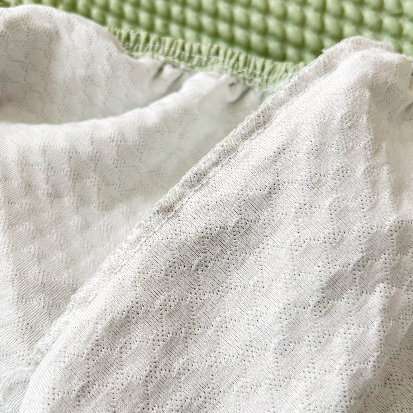 Detailed texture of Cooling Stretch Sofa Seat Cushion Covers on a green background, showcasing universal couch cushion protector design.