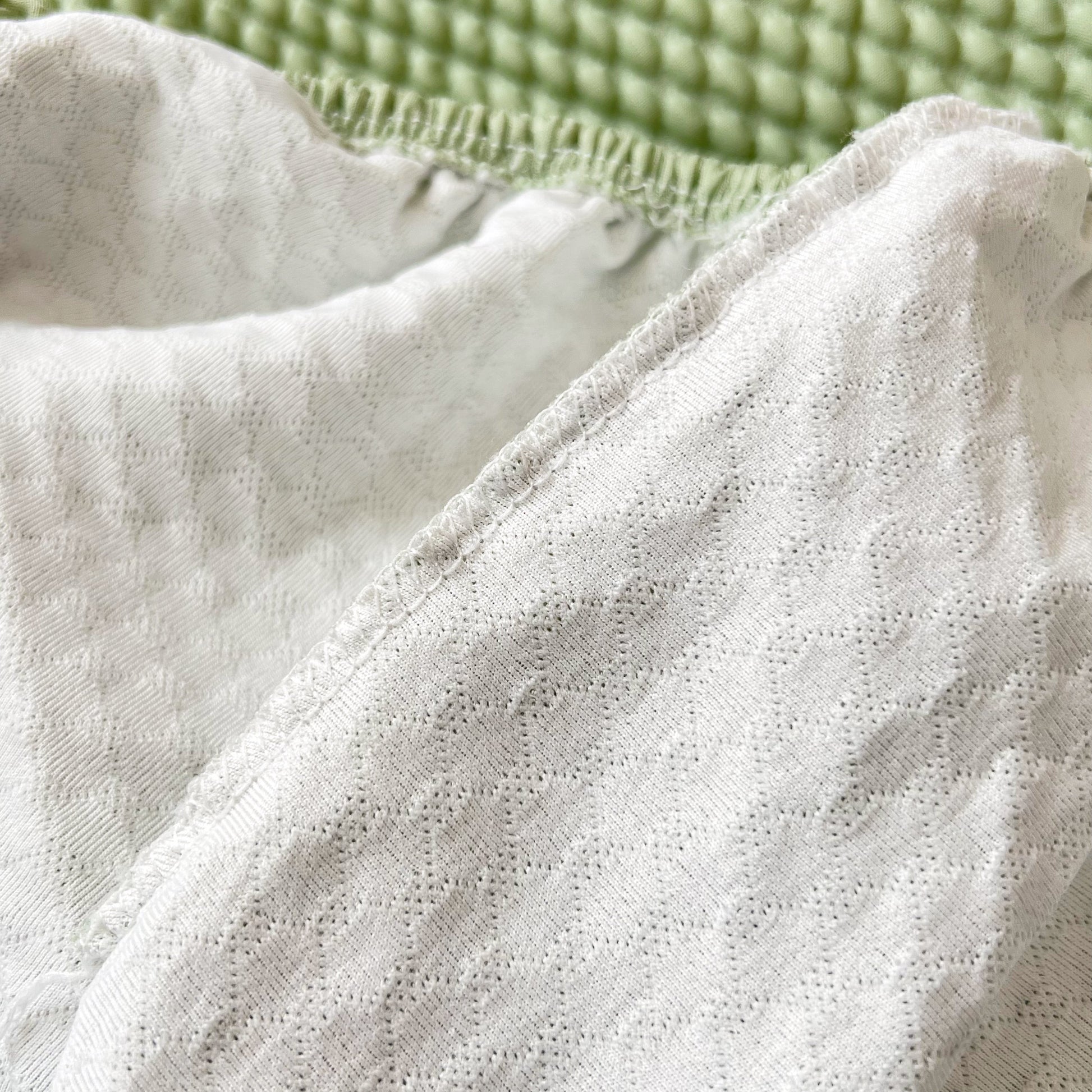 Detailed texture of Cooling Stretch Sofa Seat Cushion Covers on a green background, showcasing universal couch cushion protector design.