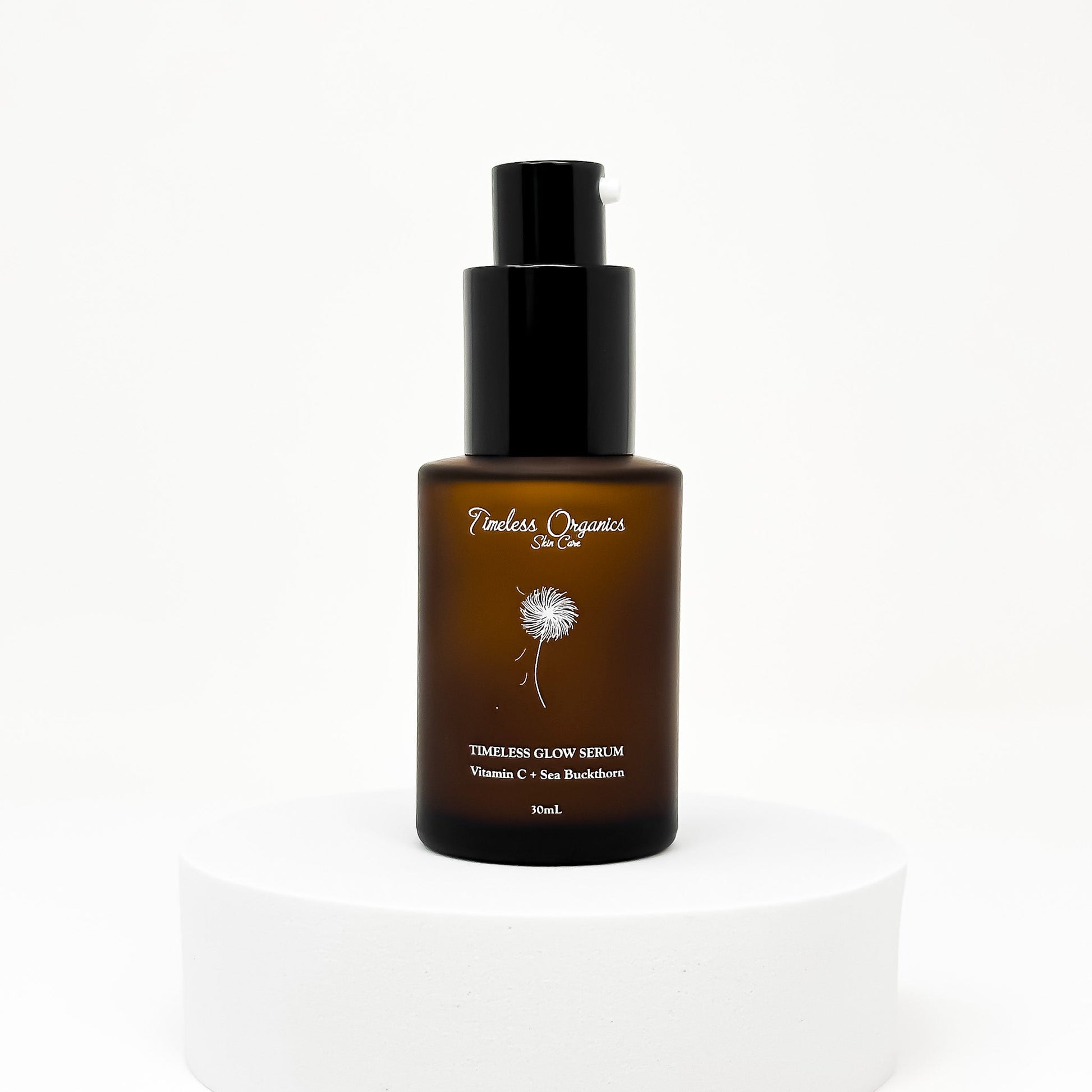 Timeless Glow Serum 30mL bottle on a white pedestal, highlighting nourishing oils and 10% Vitamin C for radiant skin.
