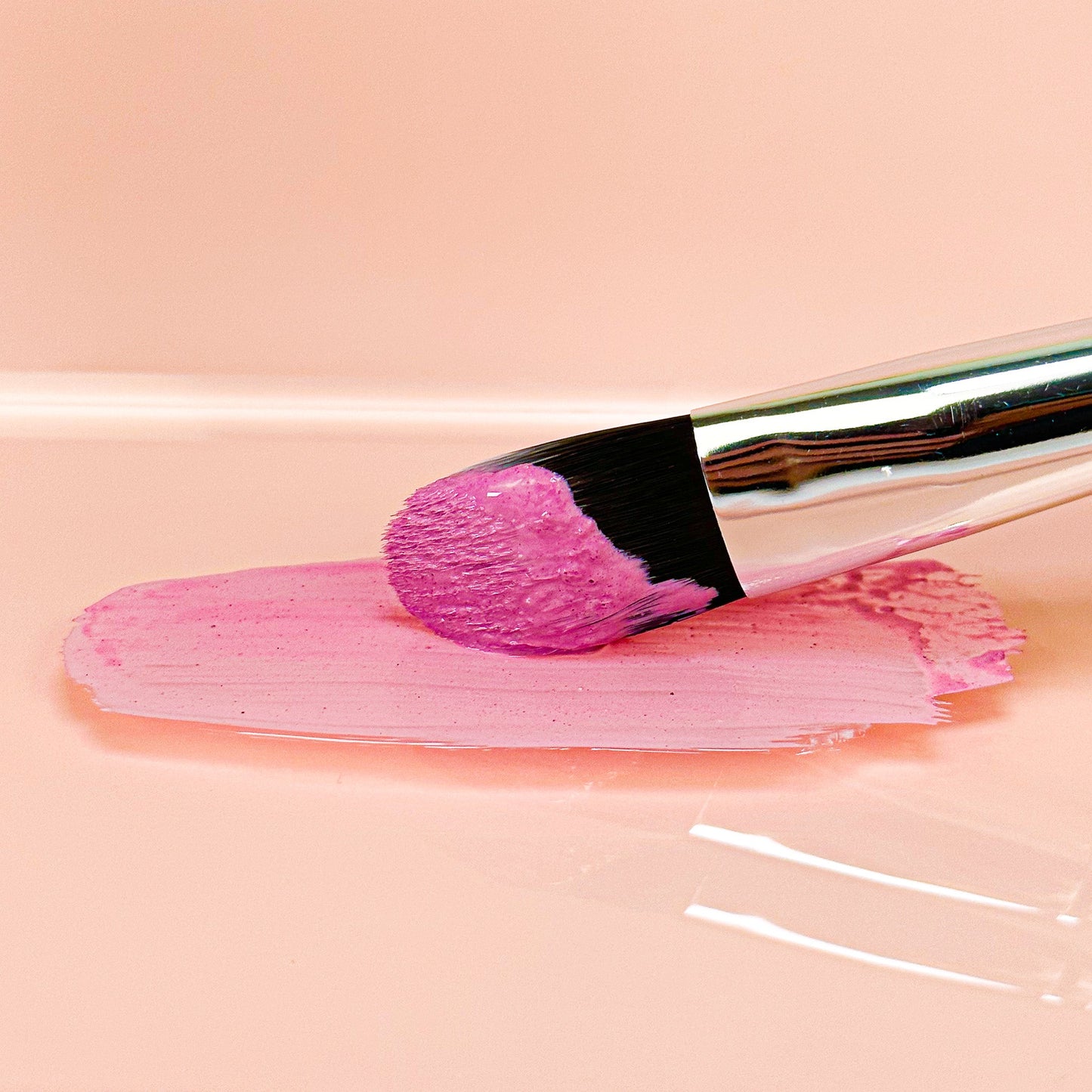 Brush applying pink Brightening Clay Mask to smooth surface, showcasing calm and revitalizing skincare benefits.