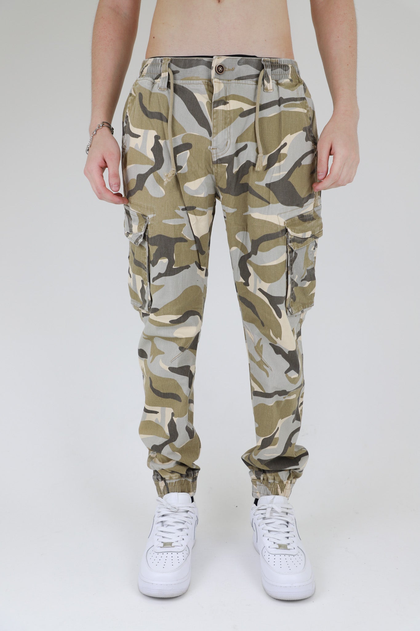 Model wearing AR1001 LIGHT CAMO CARGO JOGGERS with elastic leg openings and side seam cargo pockets.
