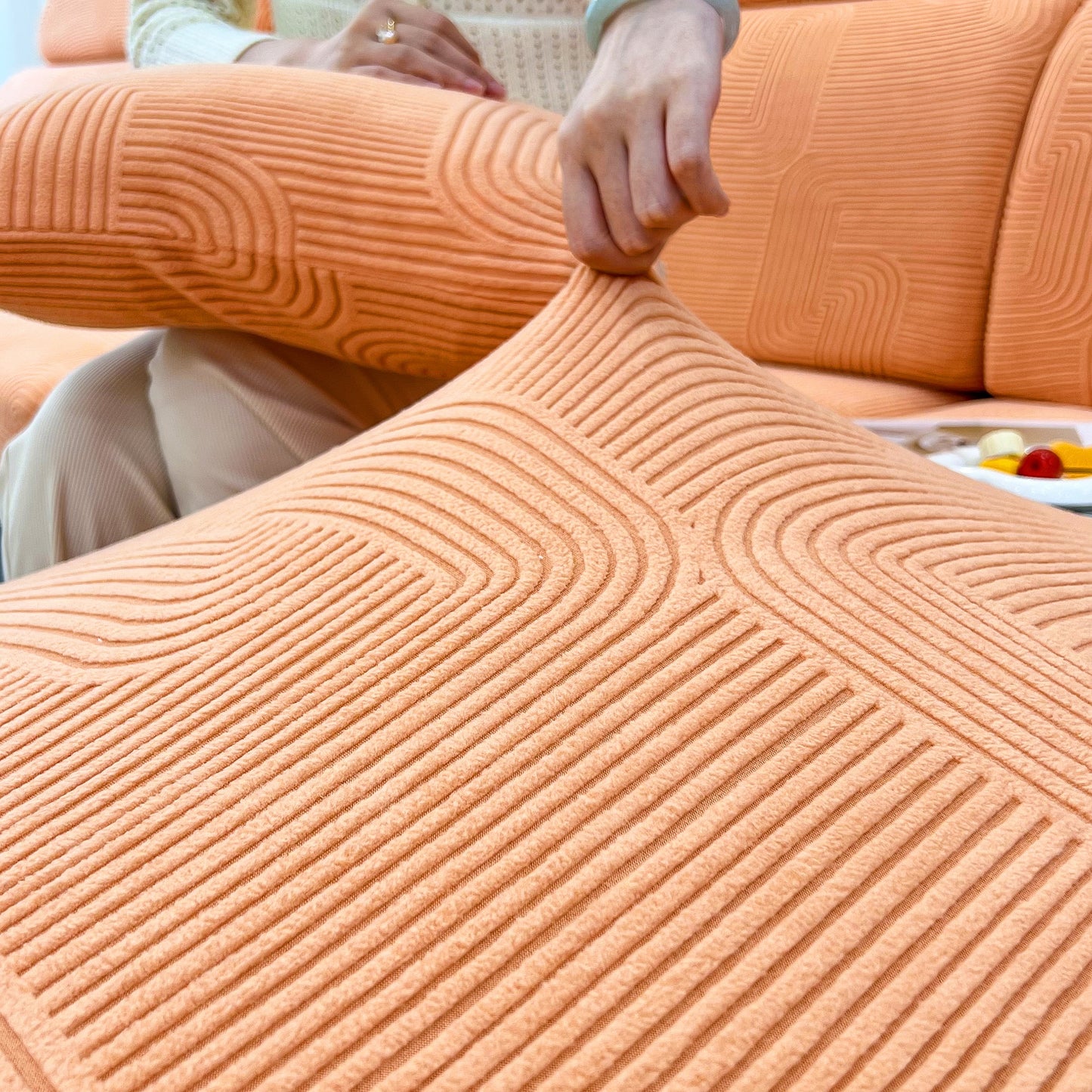 Stretch Couch Cushion Covers, Washable Chaise Lounge Sofa Slipcover fitted on an orange sofa with a person's hand adjusting the fabric