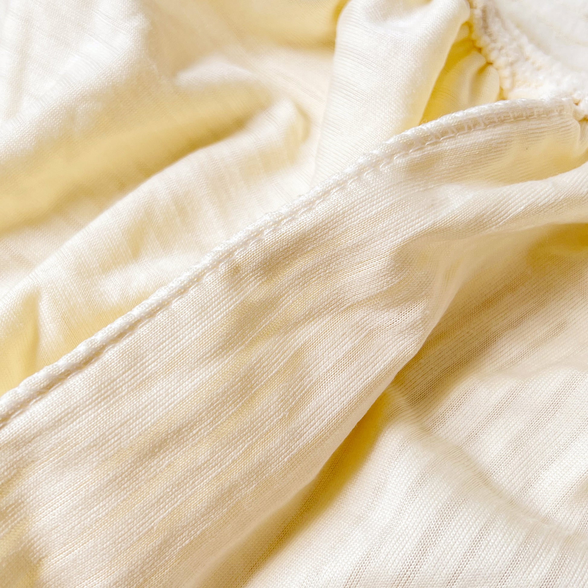 Close-up of Stretch Couch Cushion Covers, Washable Chaise Lounge Sofa Slipcover fabric in a light color, showing detailed texture.