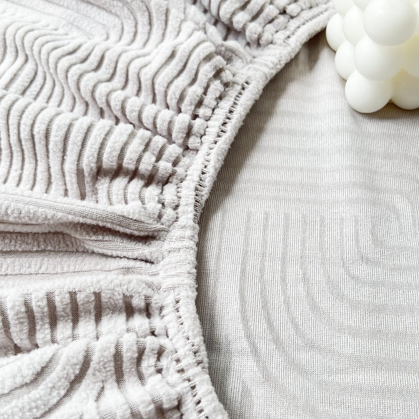 Close-up of a Stretch Couch Cushion Covers, Washable Chaise Lounge Sofa Slipcover, showcasing elastic edge and textured fabric.