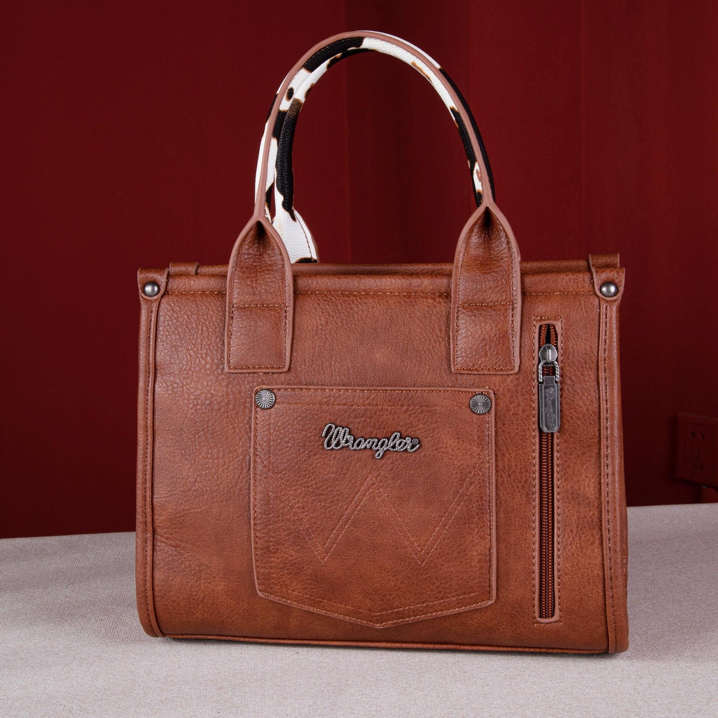 Wrangler Cow Print Concealed Carry Tote/Crossbody - Brown with leather finish and iconic logo applique.