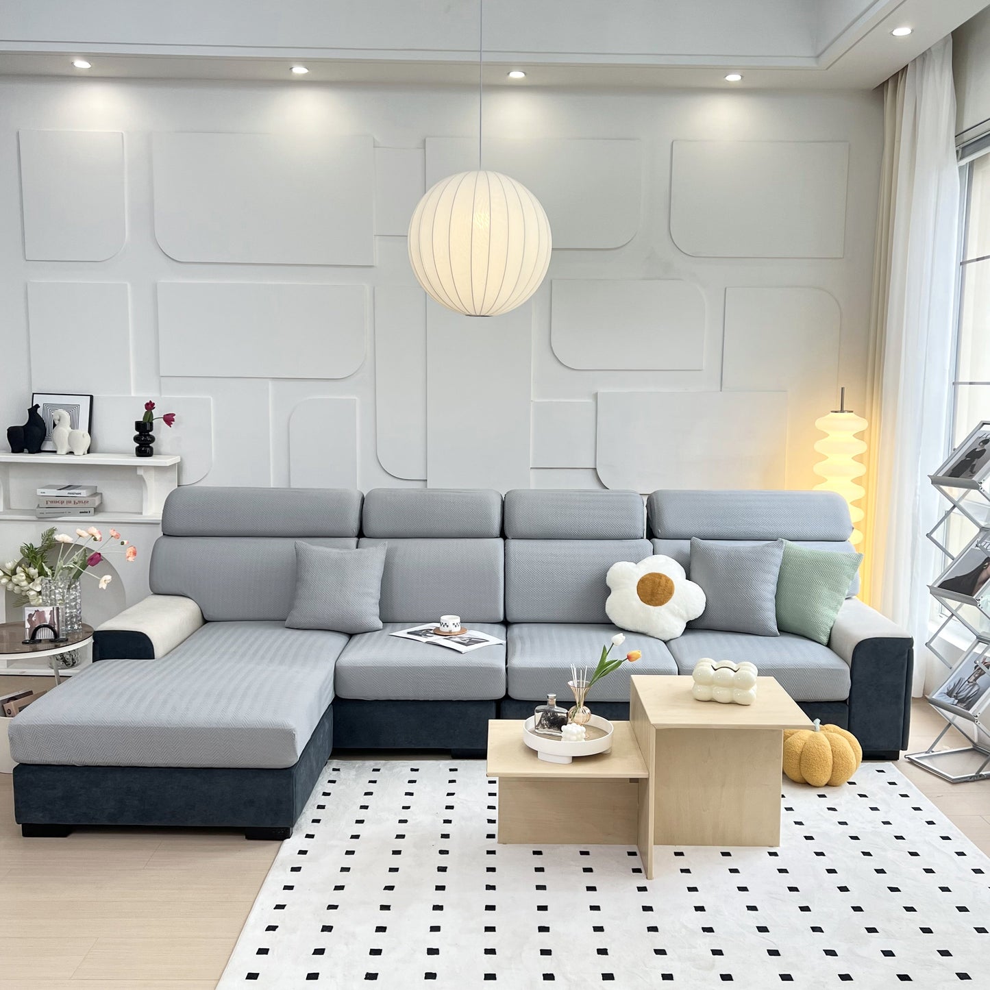 Modern living room with a gray sectional sofa and decorative cushions on a patterned rug.