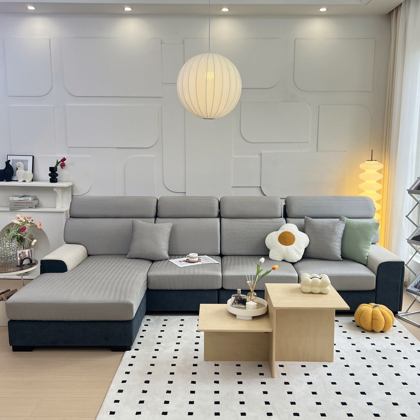Modern living room with gray sectional sofa, geometric wall design, and warm lighting.